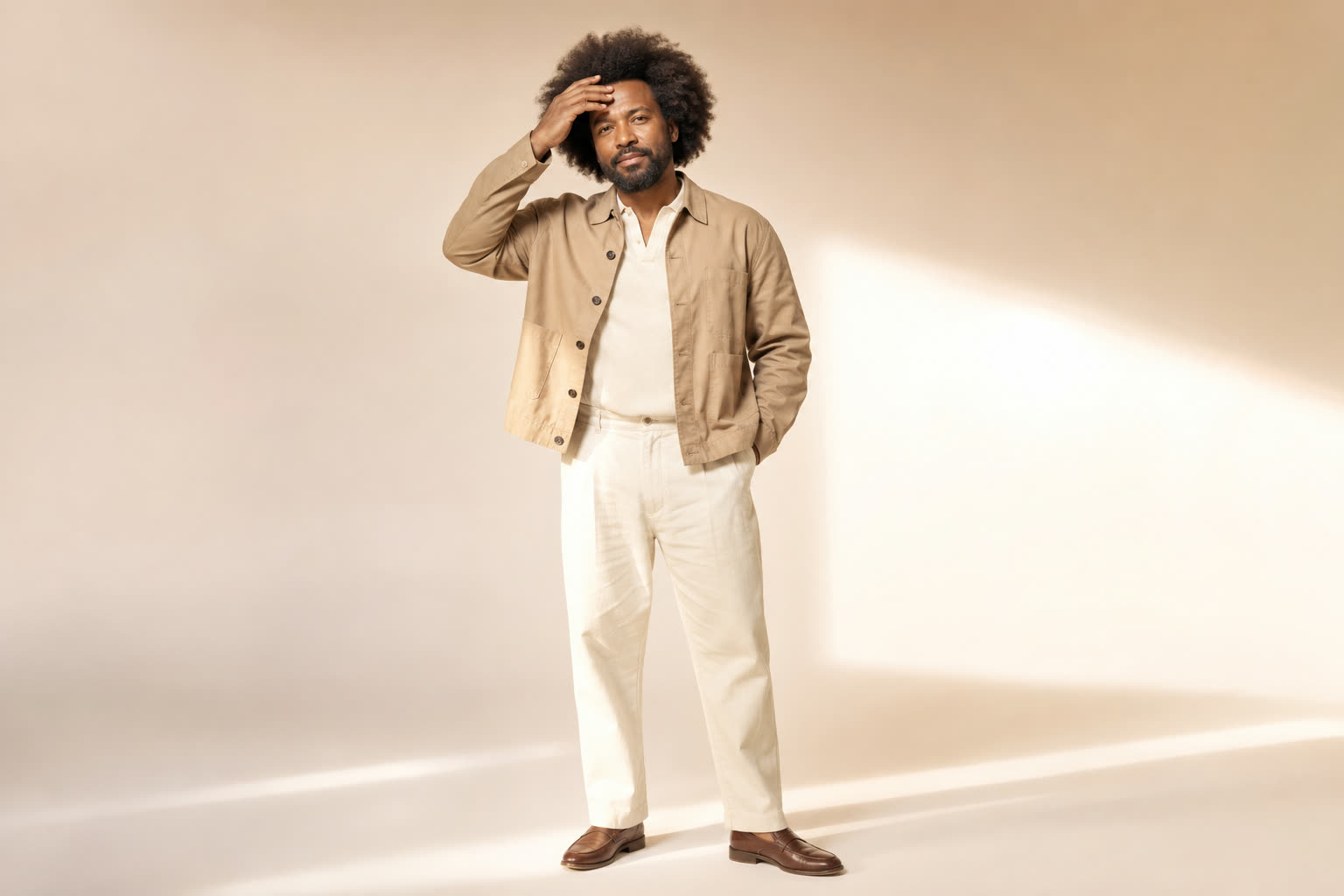 A broad, sturdy man in his 40s with a full textured afro, touching his hairline with quiet pride