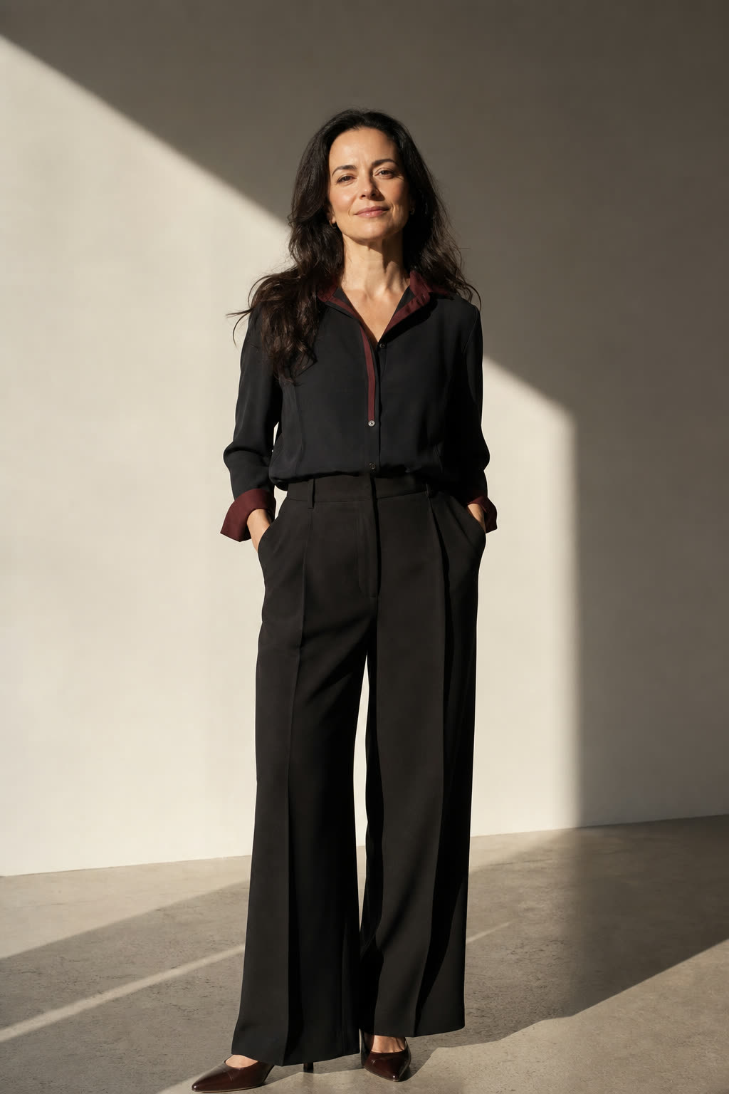 A woman in her early 40s with rich dark hair lit by dramatic warm side light