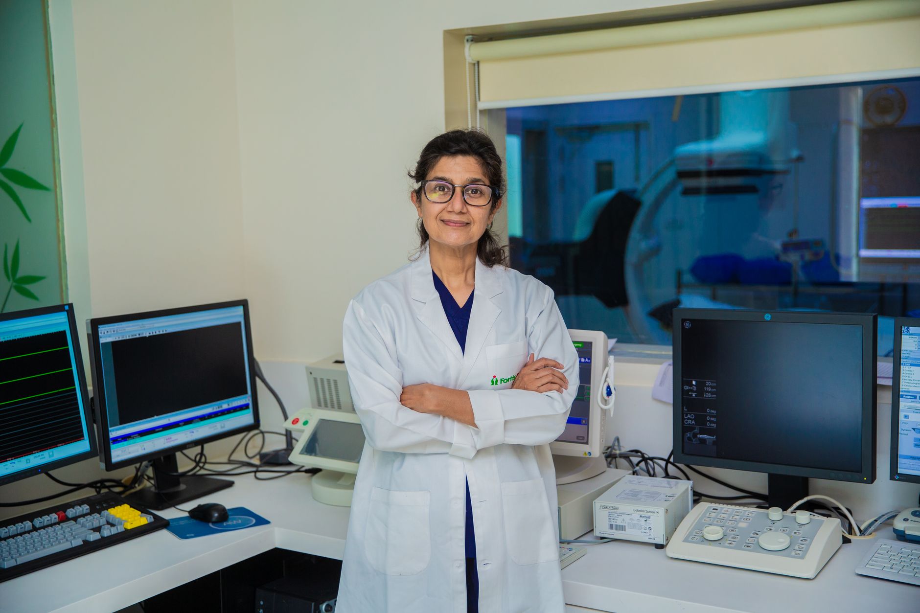 A physician in a white coat standing with her arms crossed in a modern lab