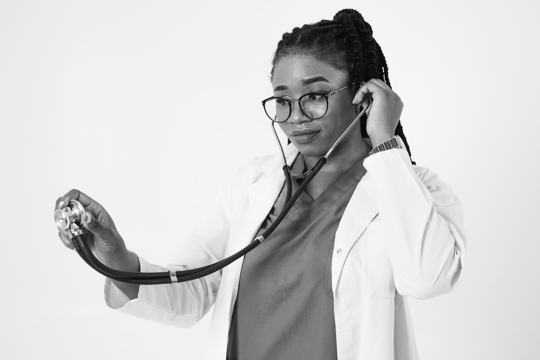 Portrait of a focused black female doctor using a stethoscope in a studio setting.