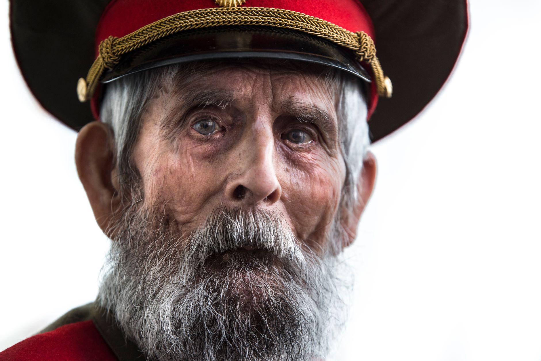Close-up portrait of a senior veteran with a full beard wearing a uniform and cap.