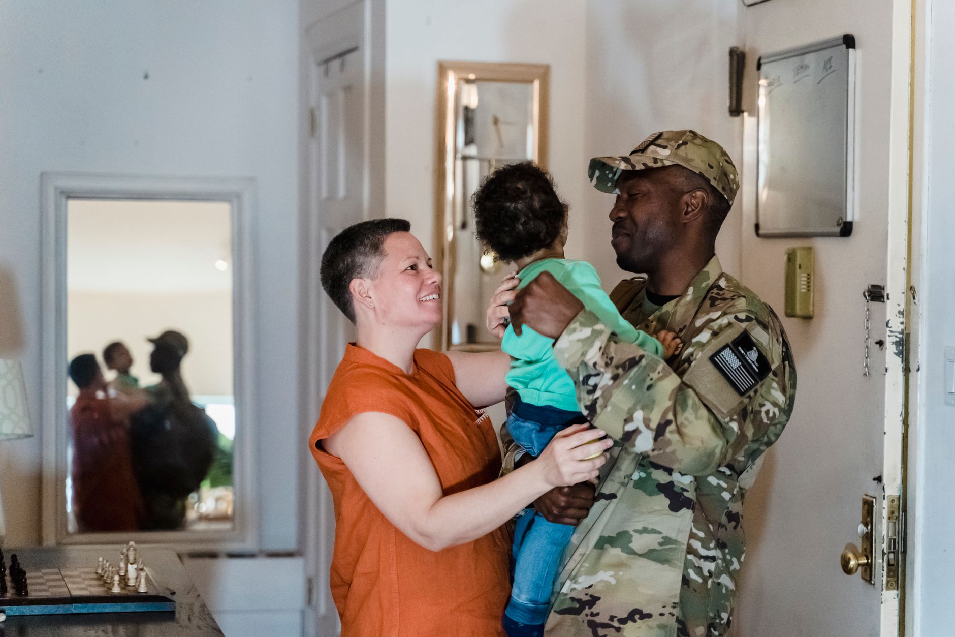 A heartwarming military family reunion with parents and child indoors.