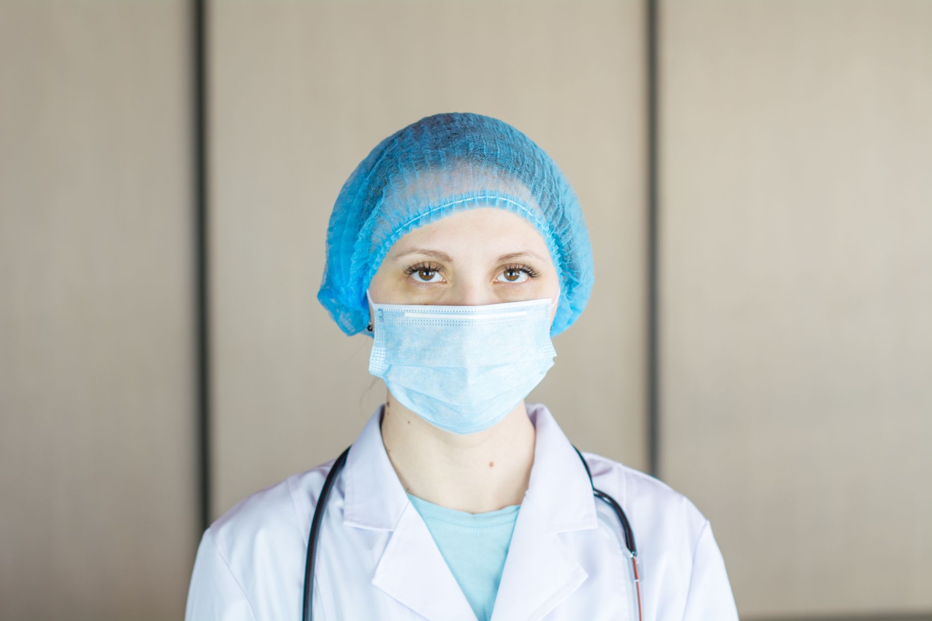Close-up portrait of a healthcare professional wearing a mask and cap, showcasing safety and care.
