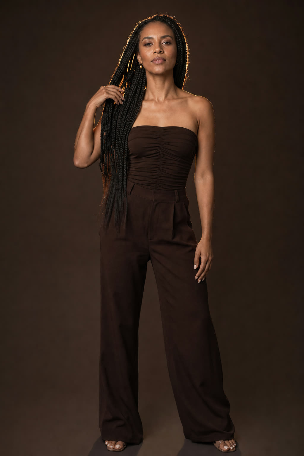 A woman with immaculate braids lifts her chin in soft studio light, whole face proud and at ease