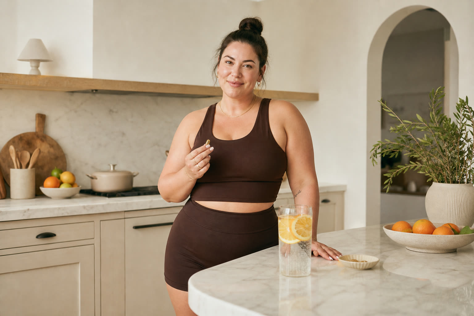 A late 20s woman with a broad-shouldered stocky build with a morning routine of a supplement and citrus water at a bright counter