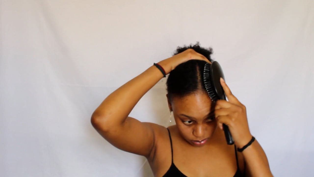 A woman styling her natural hair with her hands