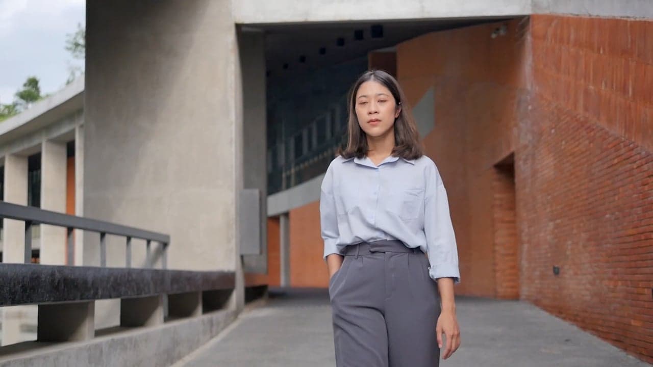 A young woman walking toward the camera with an easy confident stride